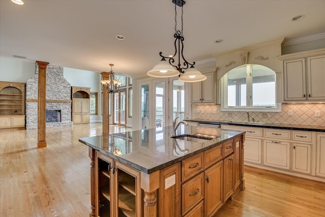 kitchen featuring a sink, cream cabinets, tasteful backsplash, dark stone countertops, and ornamental molding