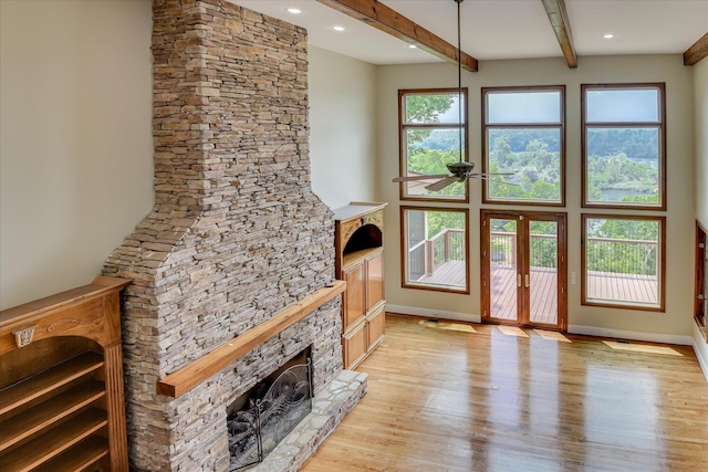 living room featuring a fireplace, beam ceiling, light wood-type flooring, baseboards, and french doors