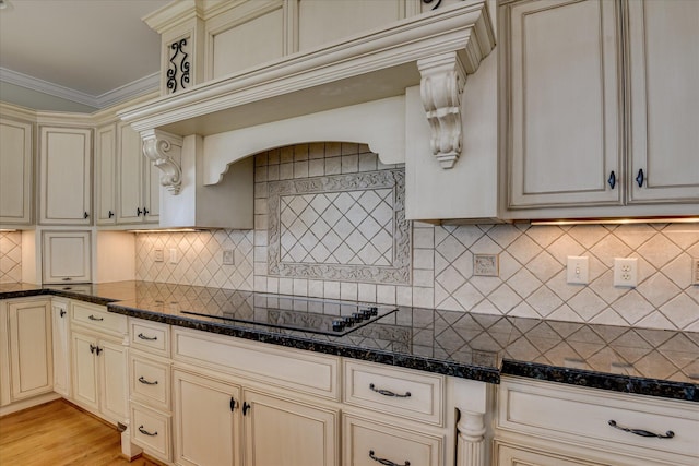 kitchen with cream cabinetry, black electric stovetop, decorative backsplash, light wood finished floors, and ornamental molding