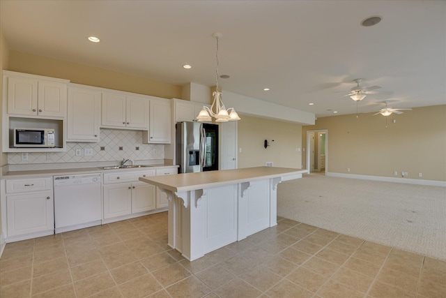 kitchen with white appliances, a sink, light colored carpet, light countertops, and white cabinetry