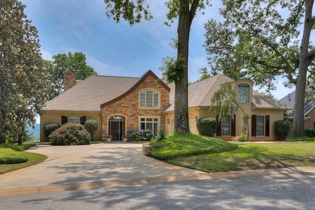 view of front of house with a chimney, curved driveway, stucco siding, stone siding, and a shingled roof