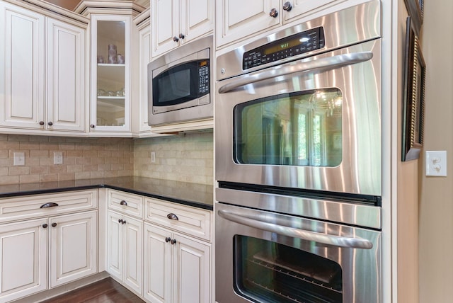 3820 Blue Springs Trce, Evans, GA 30809 - kitchen with appliances with stainless steel finishes, dark countertops, tasteful backsplash, and glass insert cabinets