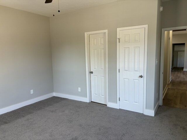 unfurnished bedroom with ceiling fan and dark carpet