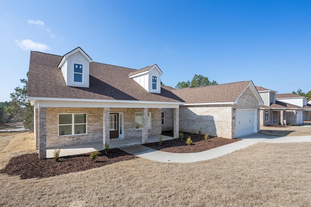 cape cod-style house featuring a garage, a front yard, and covered porch