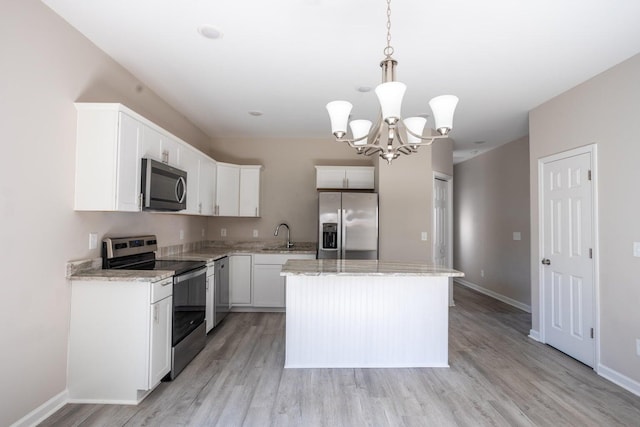 kitchen with white cabinets, a kitchen island, decorative light fixtures, stainless steel appliances, and light hardwood / wood-style flooring