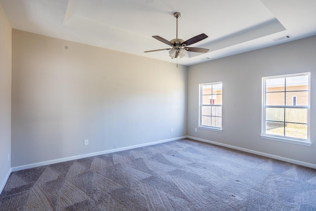 carpeted empty room featuring ceiling fan and a tray ceiling