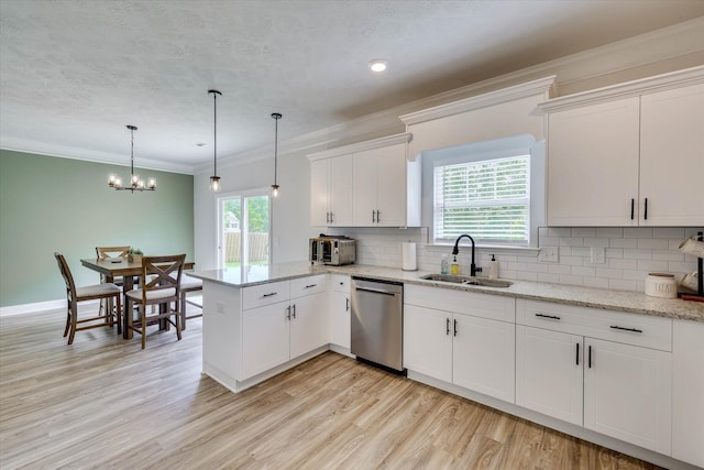 kitchen with a peninsula, a wealth of natural light, stainless steel dishwasher, and a sink