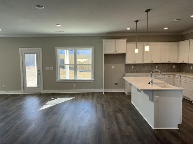 kitchen featuring white cabinets, pendant lighting, an island with sink, and sink