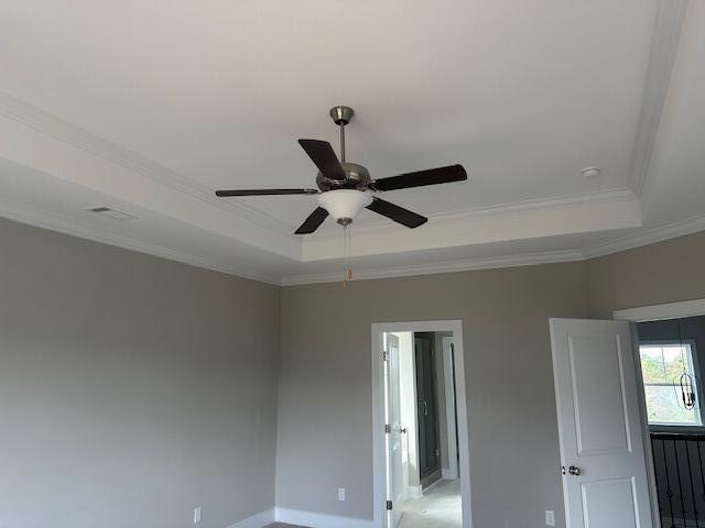 interior space with a raised ceiling, ceiling fan, and crown molding