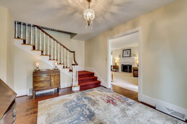 711 Augusta St, Mccormick, SC 29835 - entryway with wood finished floors, stairway, a fireplace, baseboards, and a chandelier
