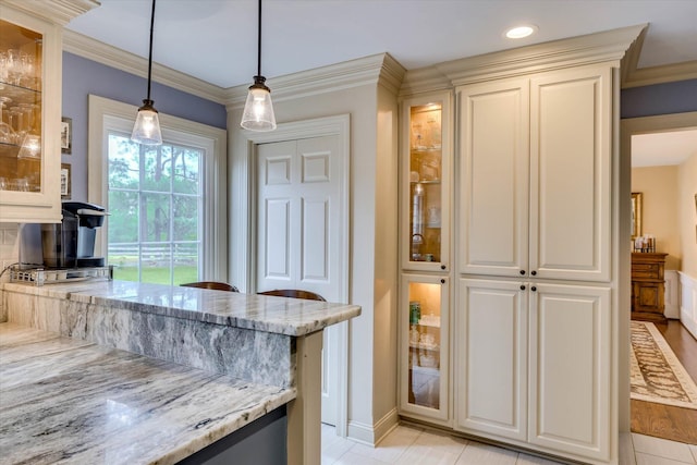 711 Augusta St, Mccormick, SC 29835 - kitchen with light stone countertops, hanging light fixtures, glass insert cabinets, ornamental molding, and white cabinets