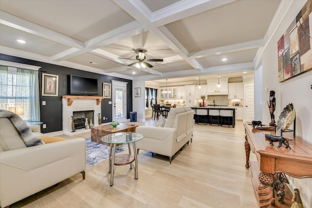 living area featuring light wood-style flooring, a fireplace, coffered ceiling, and beamed ceiling