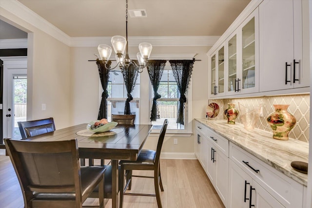 dining space featuring ornamental molding, plenty of natural light, light wood-style flooring, and visible vents