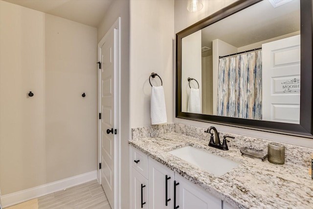 full bath featuring a shower with shower curtain, wood finished floors, vanity, and baseboards