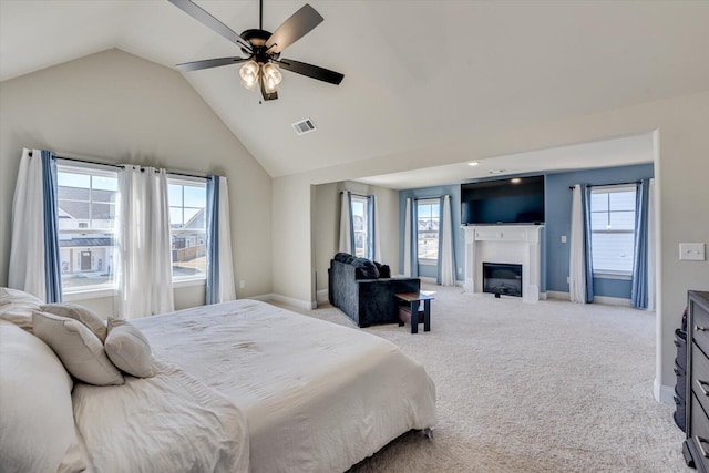 bedroom with a glass covered fireplace, visible vents, light carpet, and multiple windows