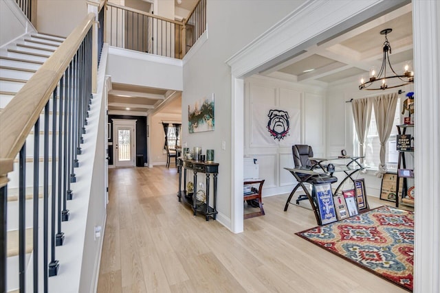 foyer entrance with a healthy amount of sunlight, coffered ceiling, a decorative wall, and wood finished floors