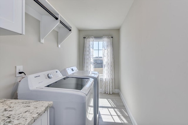 laundry area featuring separate washer and dryer, cabinet space, and baseboards