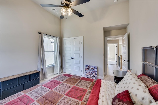 bedroom with ceiling fan, light carpet, a high ceiling, visible vents, and a closet