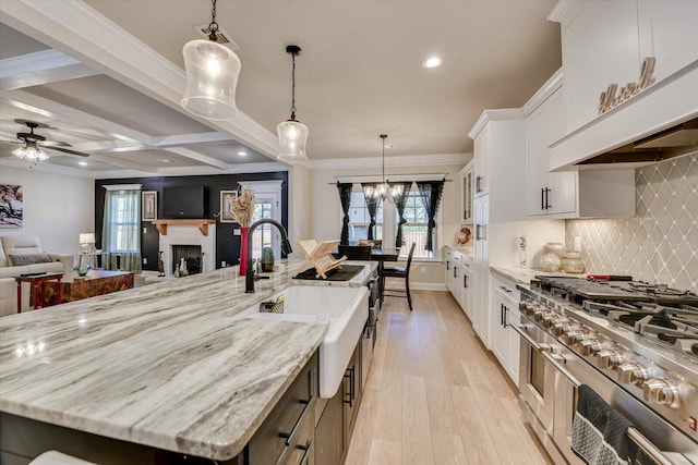 kitchen featuring a large island, stovetop, light wood-type flooring, a fireplace, and white cabinetry