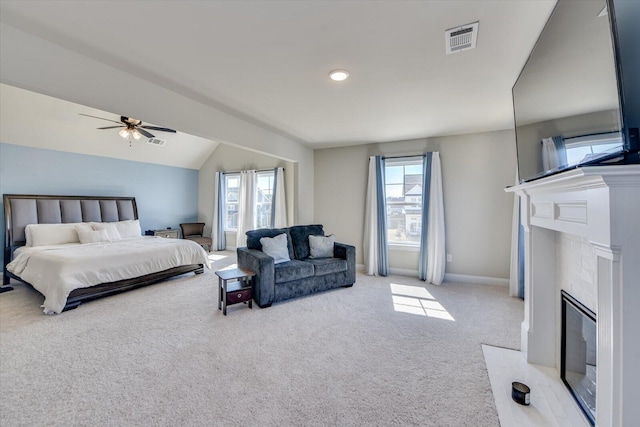 bedroom with multiple windows, a premium fireplace, visible vents, and light colored carpet