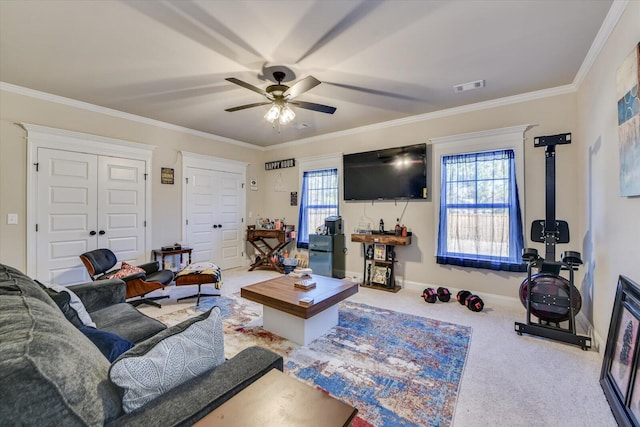 living room with a ceiling fan, visible vents, baseboards, ornamental molding, and carpet