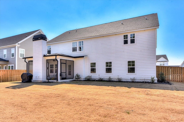 rear view of property featuring a sunroom, a fenced backyard, and a yard