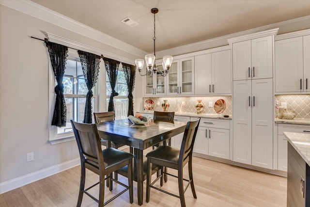 dining space featuring a chandelier, baseboards, ornamental molding, and light wood finished floors