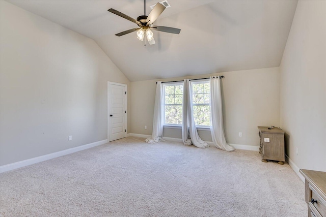 spare room featuring lofted ceiling, carpet flooring, a ceiling fan, and baseboards