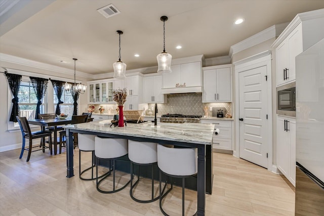 kitchen featuring tasteful backsplash, stainless steel microwave, a breakfast bar, and white cabinetry