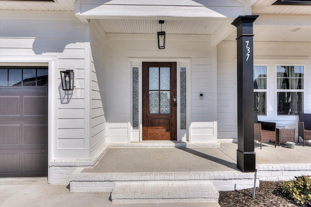 view of exterior entry with a garage and a porch