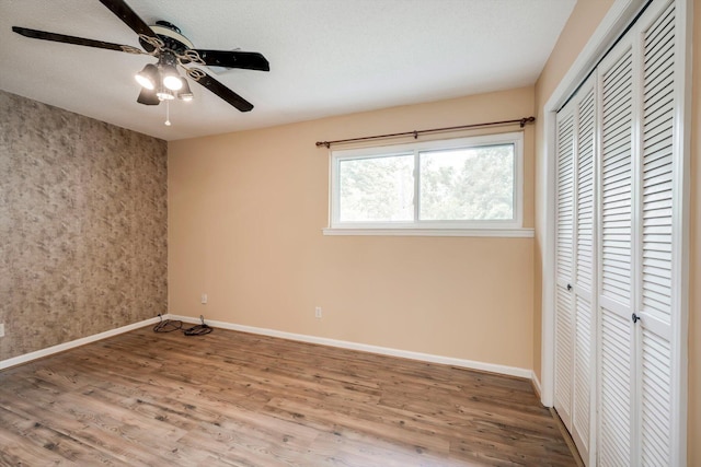 20 Teal Ct, North Augusta, SC 29841 - unfurnished bedroom with an accent wall, a ceiling fan, baseboards, wood finished floors, and a closet