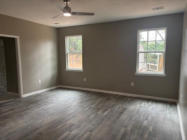 spare room featuring visible vents, baseboards, dark wood-type flooring, and a ceiling fan