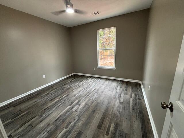 unfurnished room featuring ceiling fan, dark wood-style floors, visible vents, and baseboards