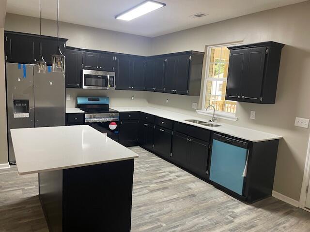 kitchen with a sink, stainless steel appliances, and dark cabinetry