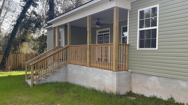 property entrance with a yard, a ceiling fan, and fence