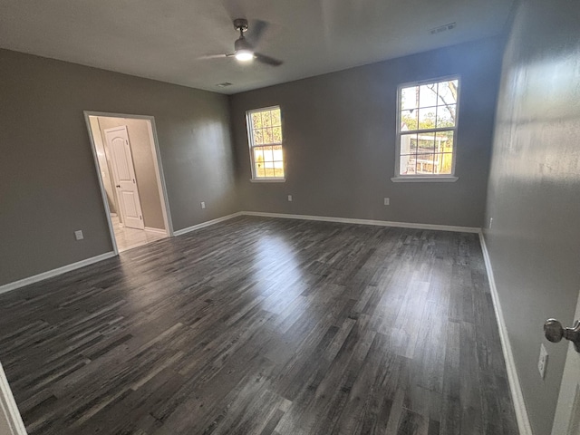 empty room featuring dark wood-type flooring, visible vents, baseboards, and ceiling fan