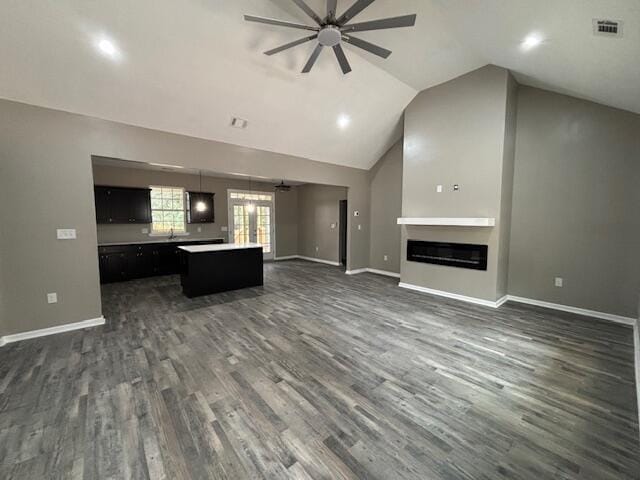 unfurnished living room with a glass covered fireplace, baseboards, and dark wood-style flooring