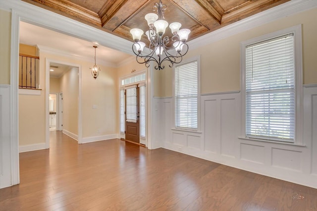 unfurnished dining area featuring coffered ceiling, crown molding, wood-type flooring, a notable chandelier, and beamed ceiling