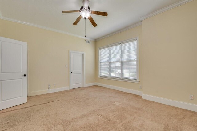 empty room featuring light colored carpet, ceiling fan, and crown molding