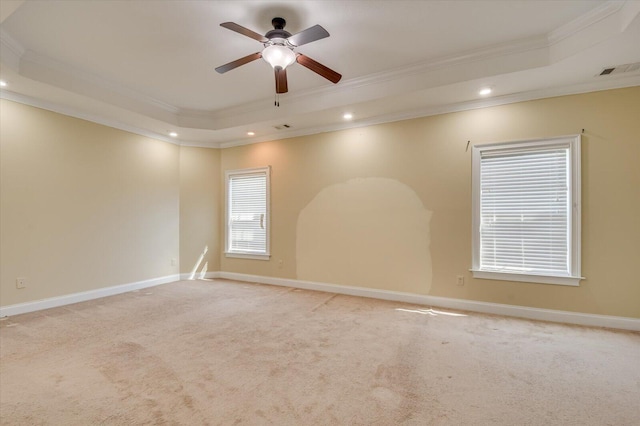 carpeted spare room featuring a raised ceiling, ceiling fan, and crown molding