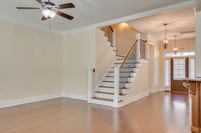 stairway featuring hardwood / wood-style floors, ceiling fan with notable chandelier, and ornamental molding