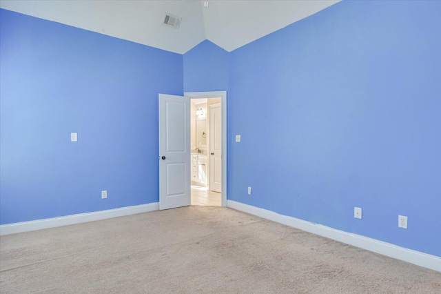 spare room featuring light carpet and lofted ceiling