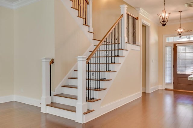 foyer entrance with dark hardwood / wood-style floors, ornamental molding, and a notable chandelier