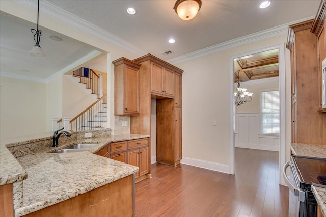 kitchen with ornamental molding, sink, and hanging light fixtures