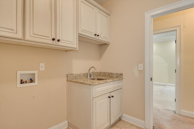 clothes washing area featuring cabinets, sink, hookup for a washing machine, and light carpet