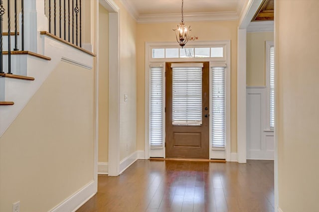 foyer with ornamental molding, dark hardwood / wood-style flooring, and a notable chandelier