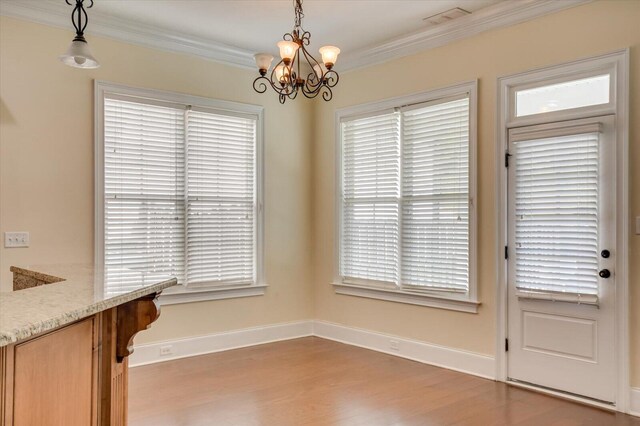 unfurnished dining area featuring hardwood / wood-style floors, an inviting chandelier, and ornamental molding