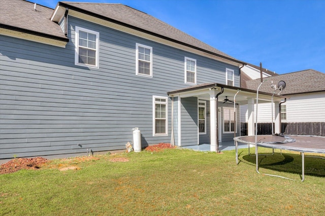 back of house featuring a lawn, a patio area, ceiling fan, and a trampoline