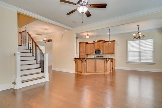 living room with wood-type flooring, ceiling fan with notable chandelier, and ornamental molding