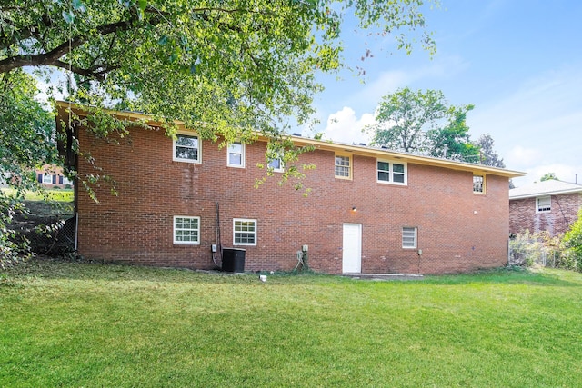 rear view of house featuring central AC unit and a lawn